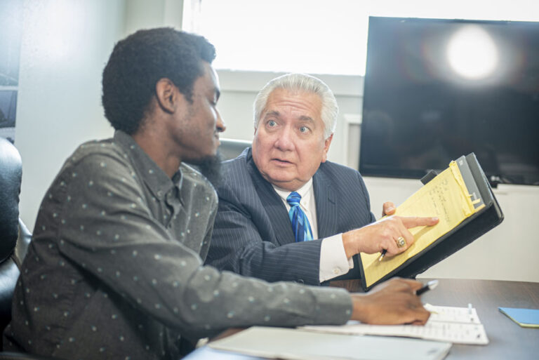 A Perkins&Perkins personal injury lawyer looking over notes and pointing case information to a legal staff member