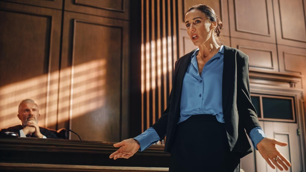 a female criminal defense lawyer presenting her case in a courtroom as the judge listens in the background