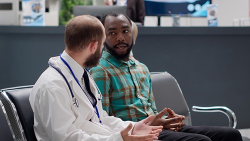 an african american man sitting and talking with a doctor for medical advice after a personal injury accident