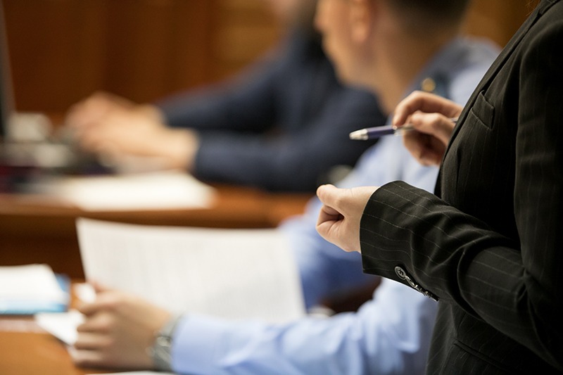 close up of a femal criminal defense lawyer's hands in the foreground during a trial in the courtroom